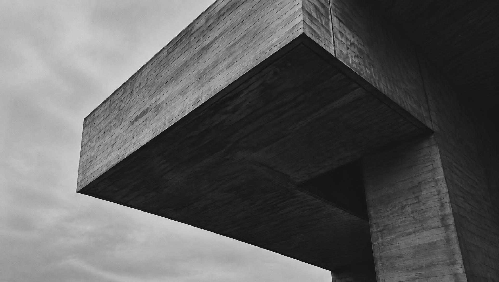 Board-formed concrete cantilever against an overcast sky